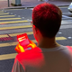 A pedestrian standing under one of the warning lights and bathed in red.